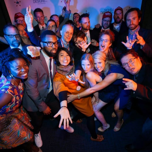 a group of Addy attendees pose in front of the step and repeat backdrop